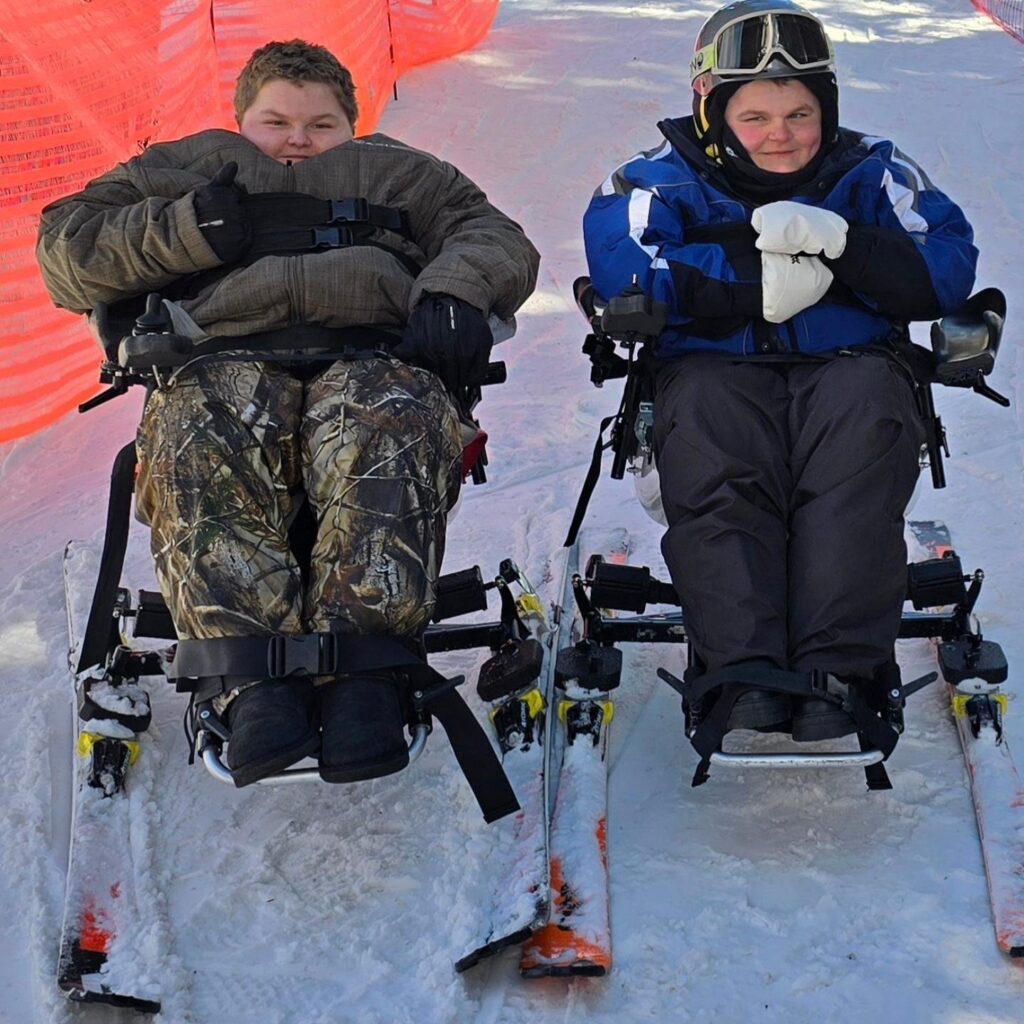 Two boys skiing down snowy hill