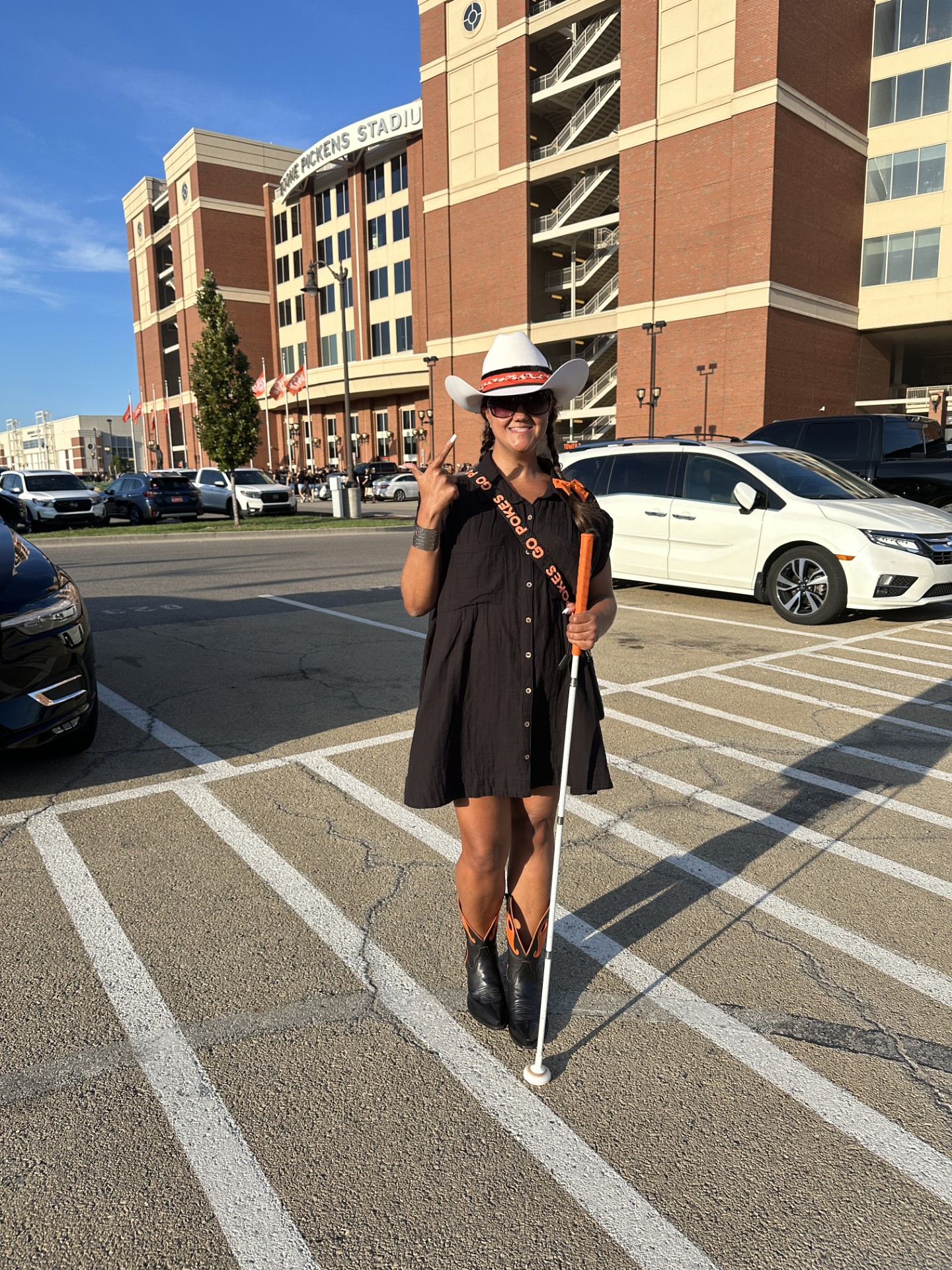 Kathryn posing with her white cane in the middle of a crosswalk, wearing a large western hat
