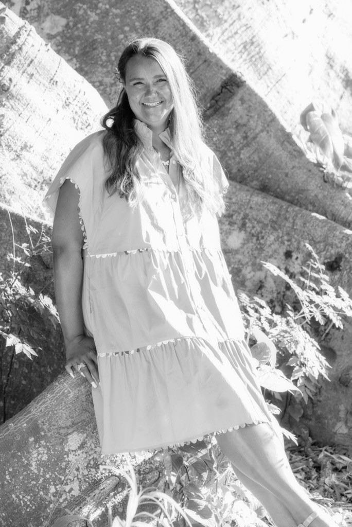 Kathryn in a dress outside, facing camera and smiling, in black and white